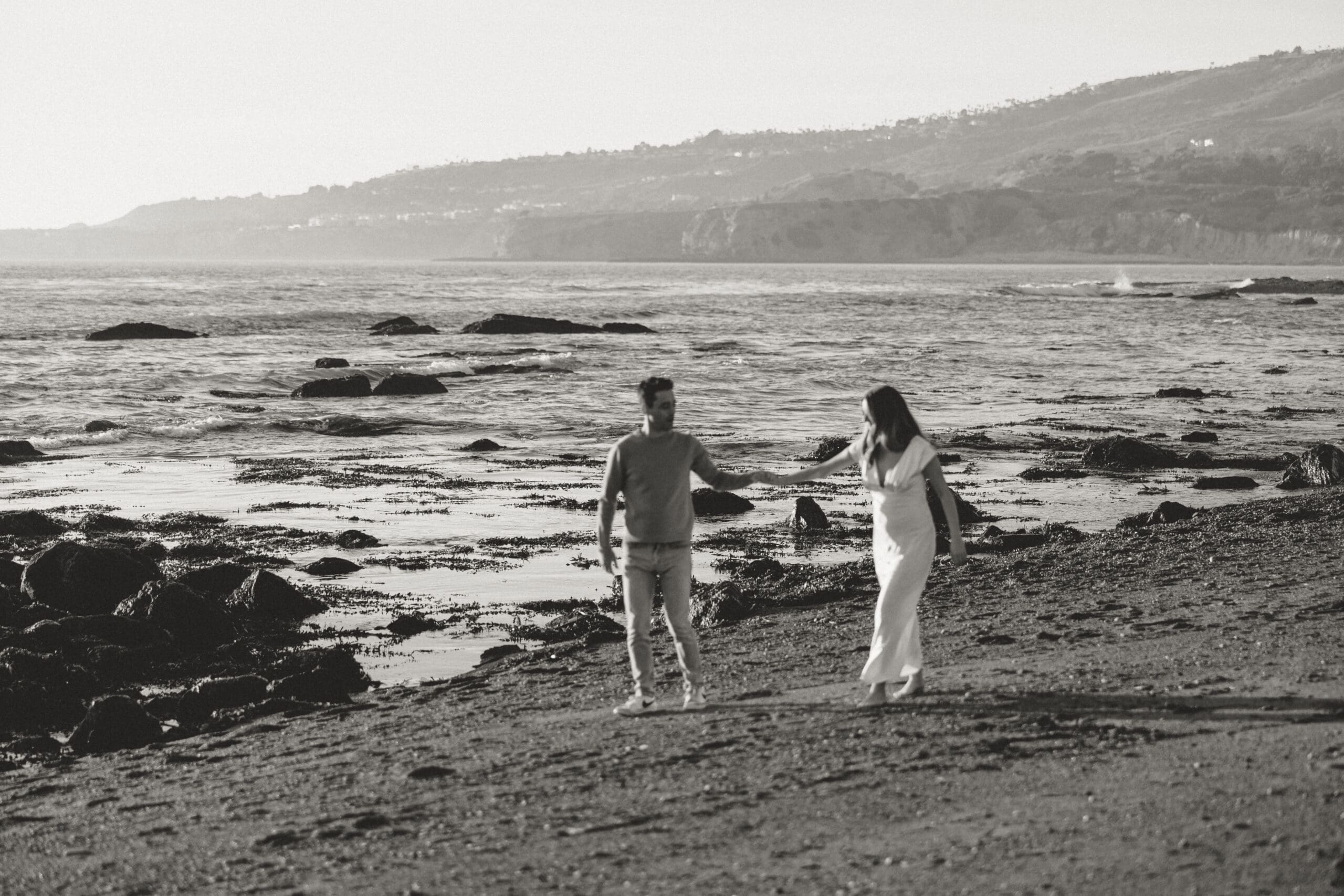 Couple walking on California beach during maternity photoshoot